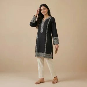 Woman wearing a black embroidered cotton kurti with detailed ethnic embroidery and full sleeves paired with white embroidered straight pants.