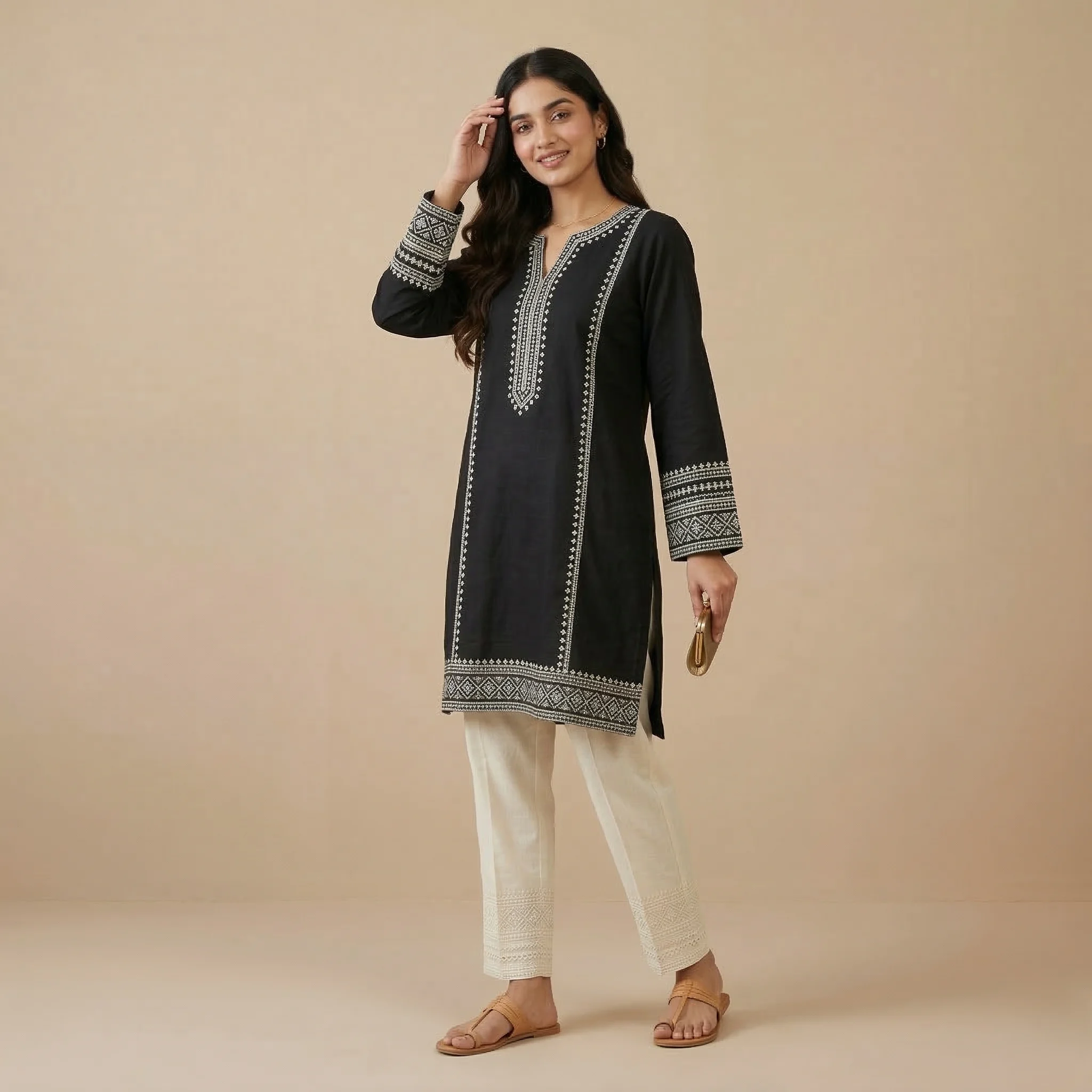 Woman wearing a black embroidered cotton kurti with detailed ethnic embroidery and full sleeves paired with white embroidered straight pants.